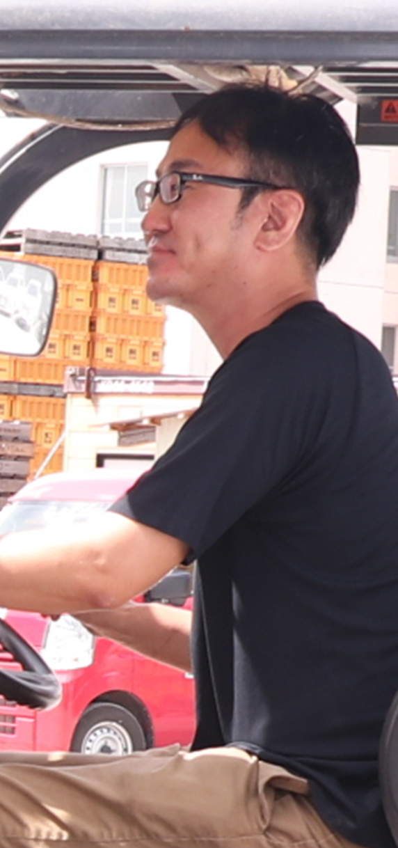 フォークリフトを運転する、メガネをかけた男性